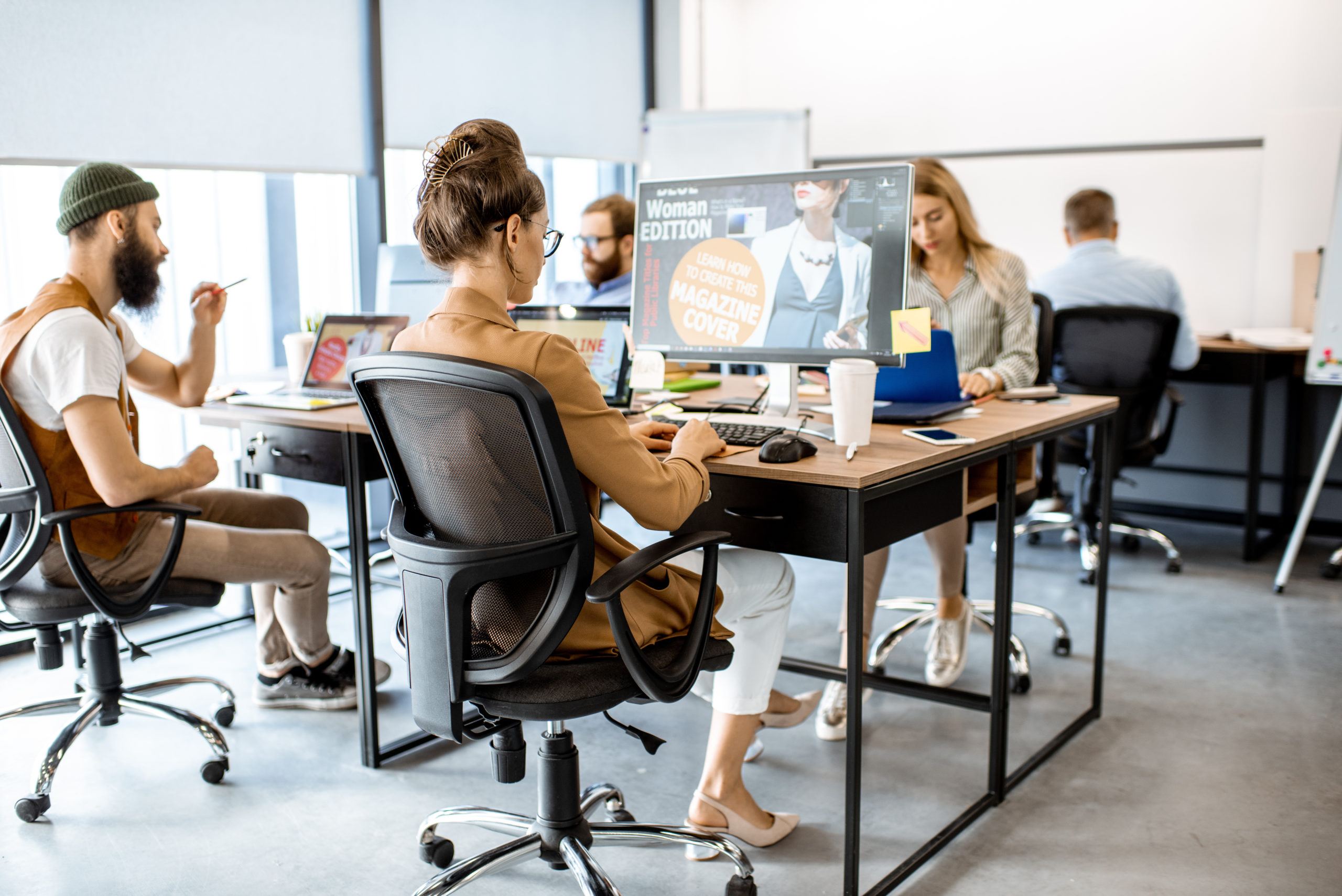 Group of diverse and creative colleagues working on computers in the modern office or coworking space, working on web design